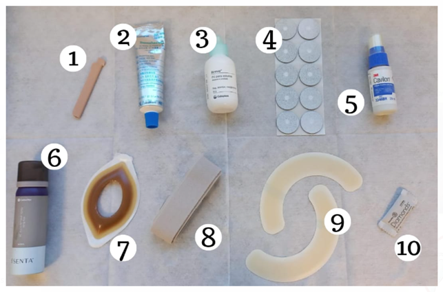 Kit com 10 produtos para cuidado de pessoas estomizadas. Imagem com 10 produtos utilizados no cuidado de pessoas estomizadas, dispostos sobre uma superfície branca e numerados de 1 a 10. Os itens incluem espátula, cremes, soluções, adesivos, barreiras protetoras, spray fixador, base adesiva para estomia, faixa elástica, moldes semicirculares de barreira protetora e removedor de adesivo.