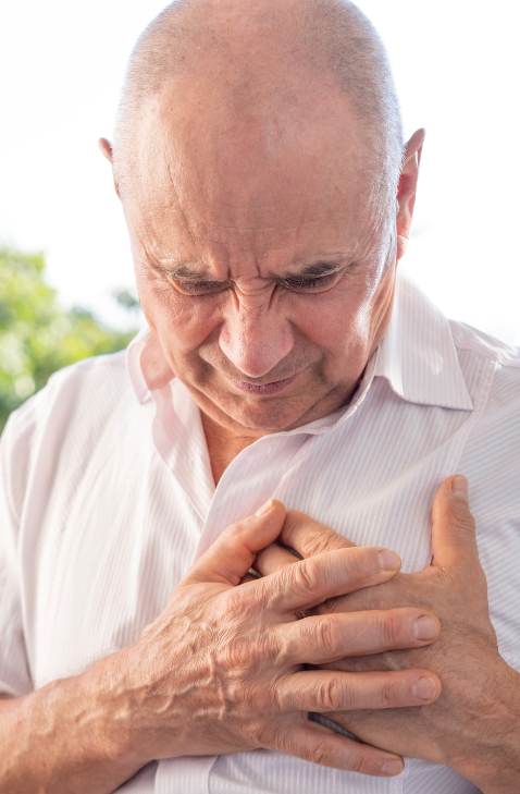 Sintoma de aterosclerose: dor no peito em paciente idoso Paciente idoso segurando o peito com expressão de dor, sugerindo dor torácica causada pela aterosclerose.